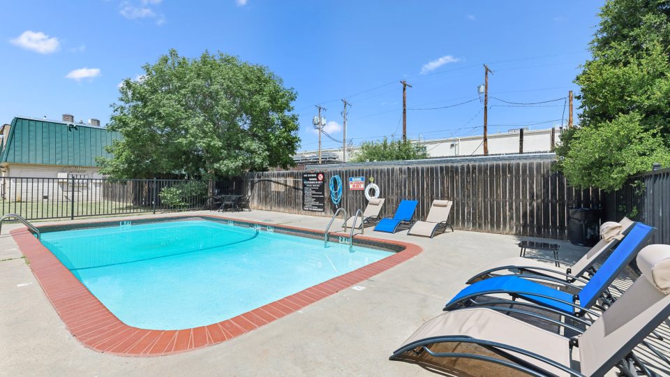 a pool with lounge chairs and a fence around it at The Crestwood Terrace