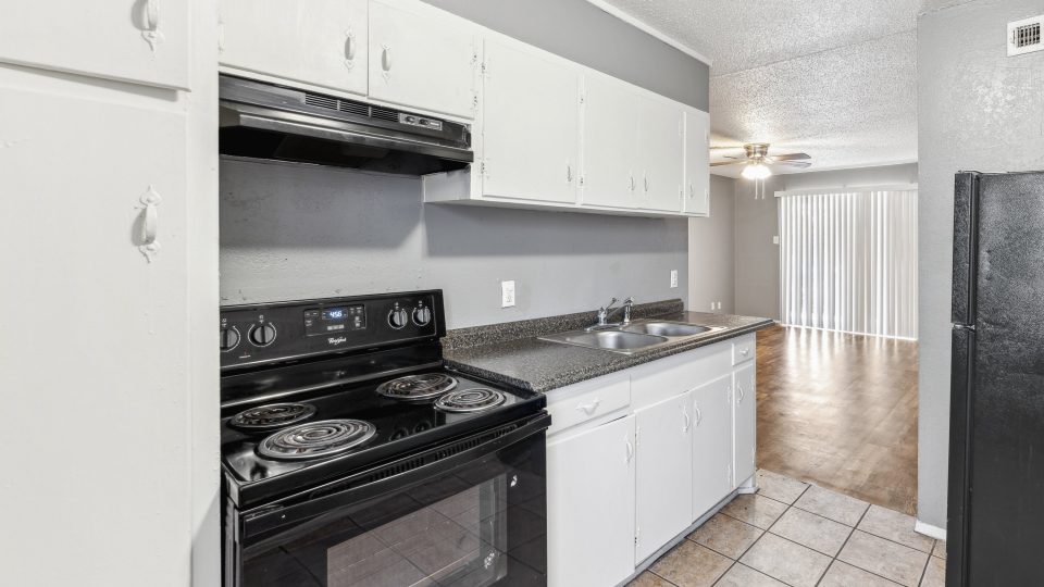 a kitchen with black appliances and white cabinets at The Crestwood Terrace