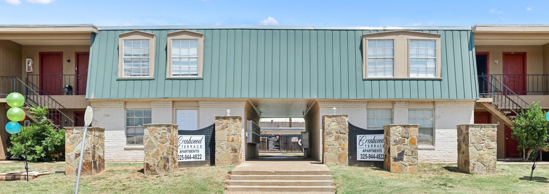 the exterior of an apartment building with a green lawn at The Crestwood Terrace